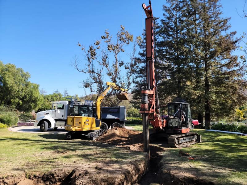 Drill rig and excavator at work on a new septic system installation on a residential lot