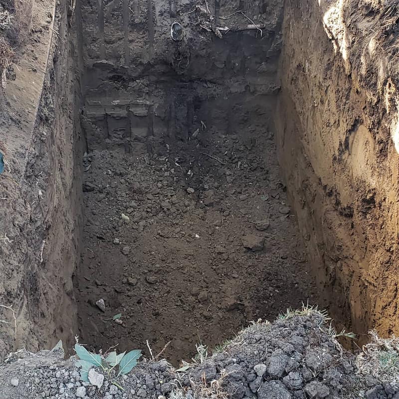 Deep excavated trench with gravel at the bottom, prepared for leach line work