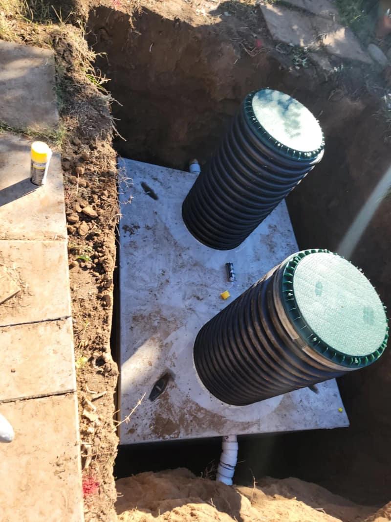 Concrete septic tank with two plastic risers installed in an open excavation