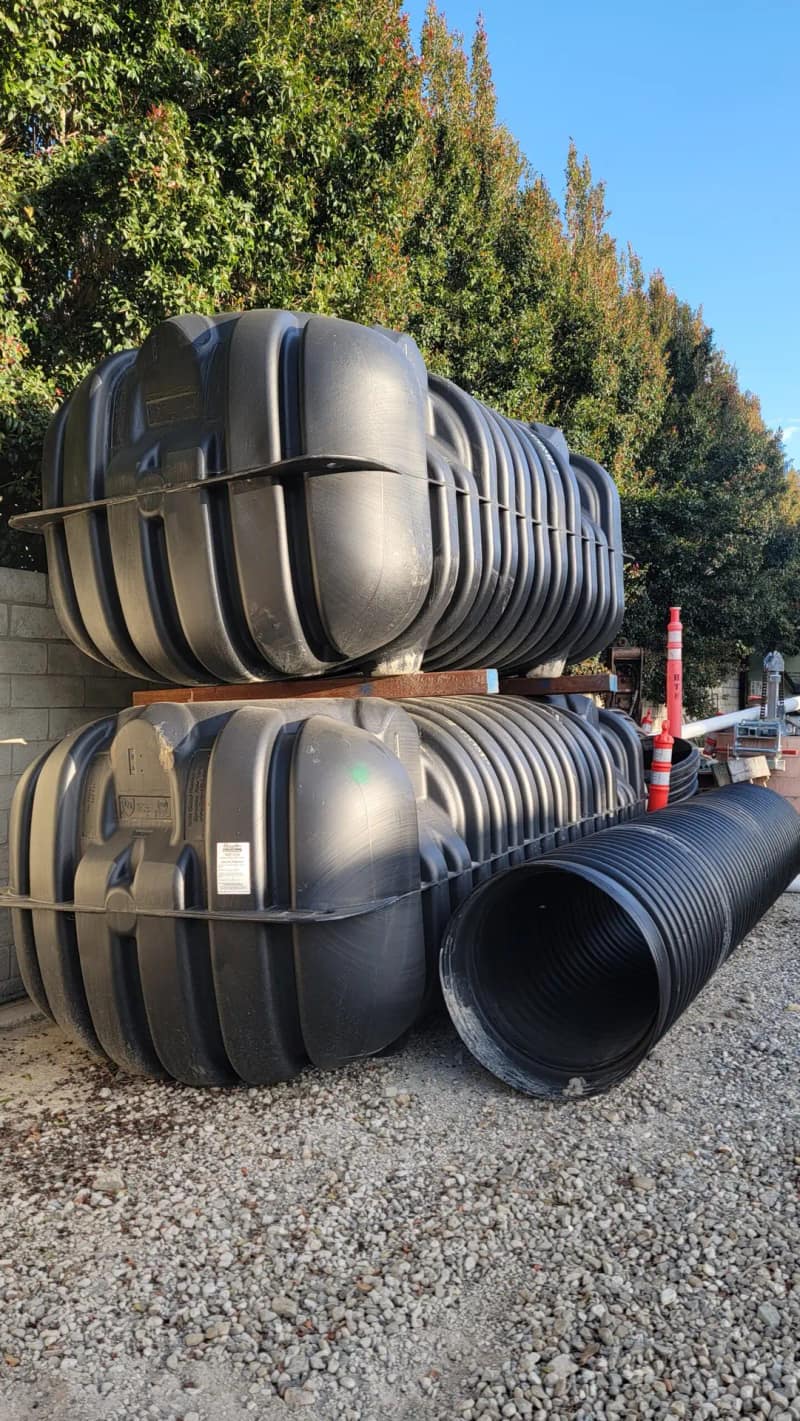Stack of black Roth multi-layer septic tanks waiting at a job site