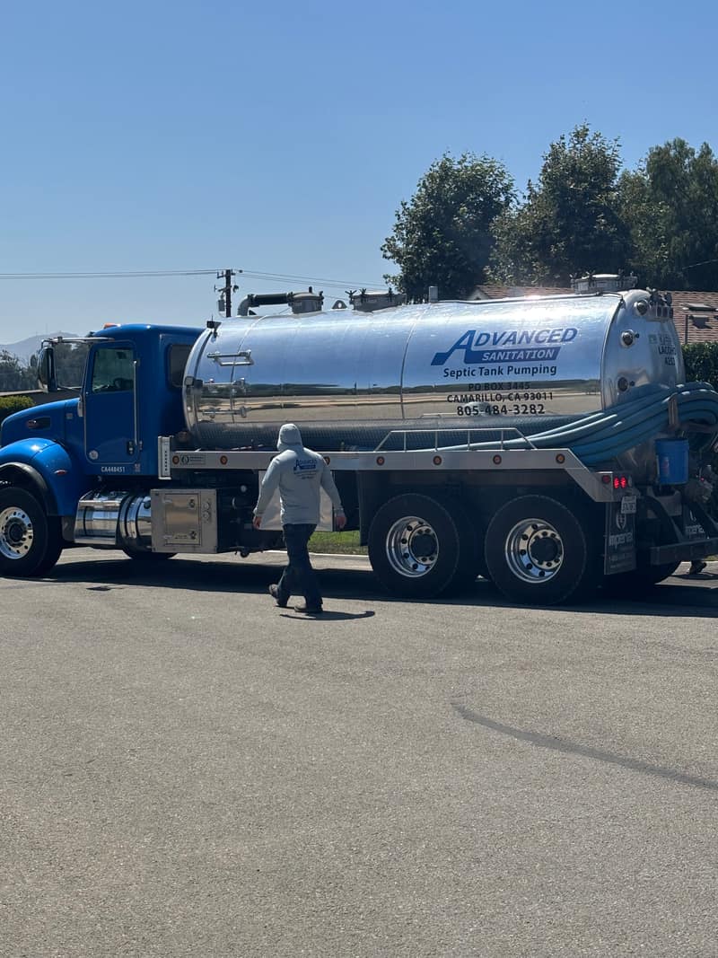 Advanced Sanitation pump truck at a job with a technician walking toward the tank
